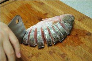 將鱸魚(yú)清洗干凈，從脊椎處切斷至腹部，腹部保留1cm左右不要切斷。